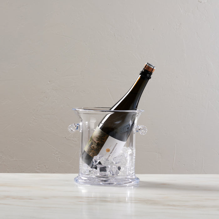 Clear glass ice bucket with two handles containing ice and a dark wine bottle.