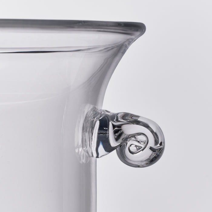 Clear glass ice bucket with curved rim and ornate scrolled handle detail.