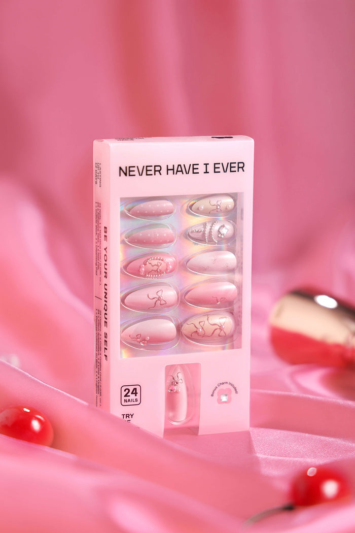 Pink almond press-on nails with bow designs and pearl accents in packaging.
