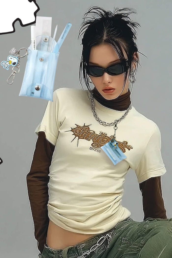 Peanuts Faux Nail Fix-It Kit with nail glue, file, and cuticle pusher in a light blue pouch with Snoopy keychain.