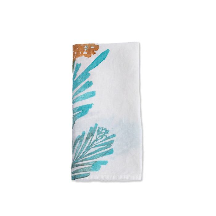 White linen napkin with teal and brown pine branch and evergreen print design.