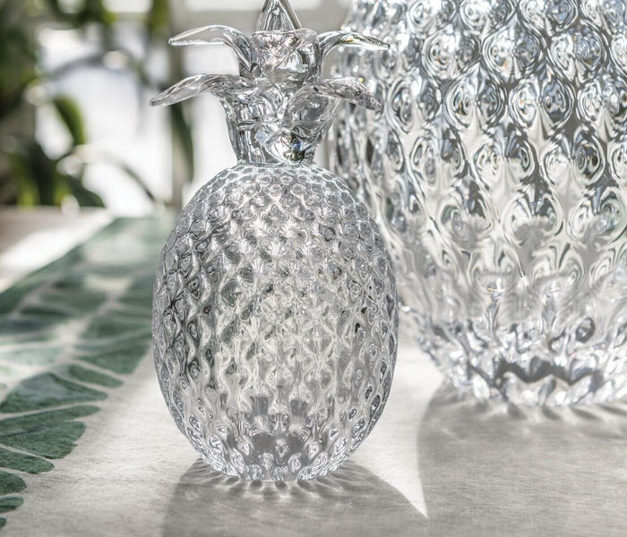 Clear glass pineapple-shaped decorative container with textured diamond pattern and metal crown stopper.
