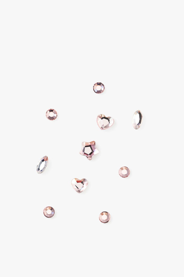 Pink tooth gems in various shapes including round, heart, and star, on a white background.