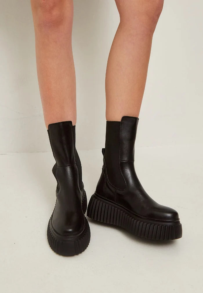 A stylish pair of black Chelsea boots with a ribbed sole, featuring a platform design, perfect for women's footwear fashion.