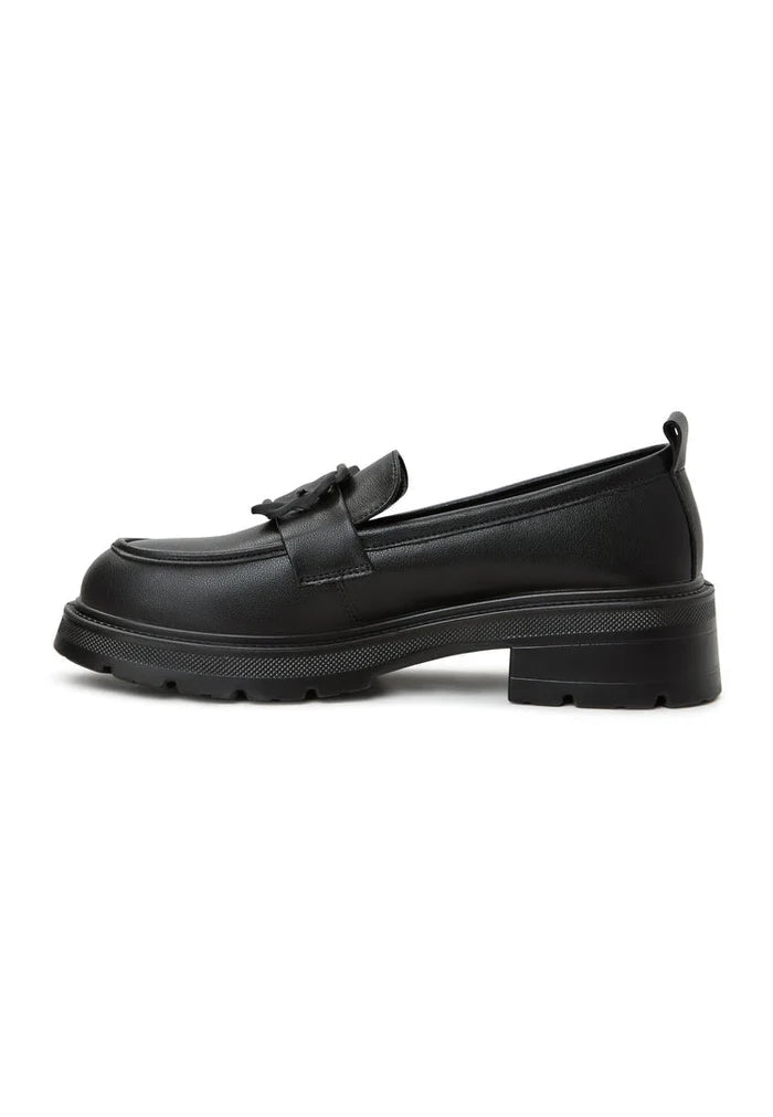 A woman wearing black platform loafers with a traditional sari, showcasing a stylish fusion of women's footwear fashion.