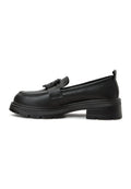A woman wearing black platform loafers with a traditional sari, showcasing a stylish fusion of women's footwear fashion.