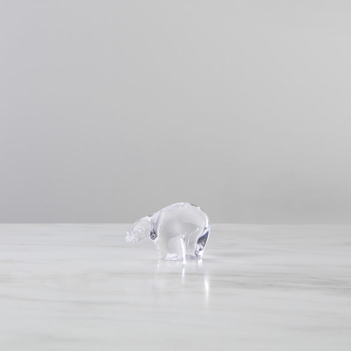 Small clear glass polar bear figurine shown from the side on a white surface.
