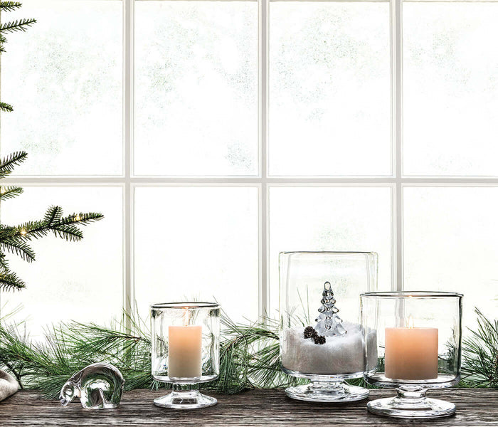 Small white polar bear figurine displayed on wooden surface with candles and evergreen branches.