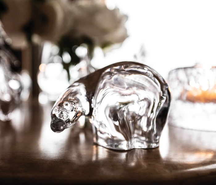 Small clear glass polar bear figurine with detailed molded features, displayed on a dark surface.