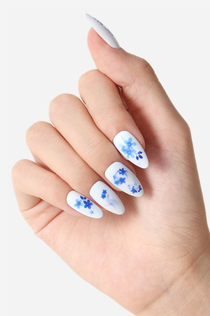 White press-on nails with delicate blue floral designs, almond shape.