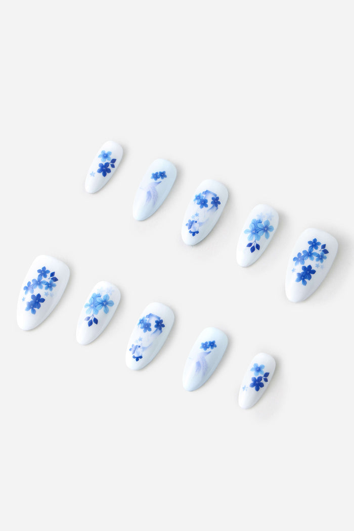 White press-on nails with delicate blue floral designs and subtle accents.