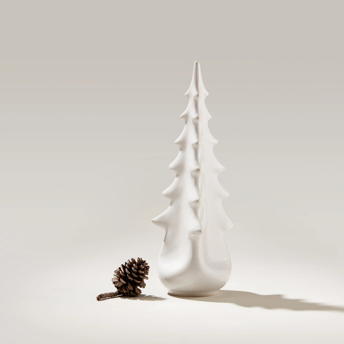 White ceramic tree-shaped vessel with tiered branches and rounded base, displayed next to a pinecone.