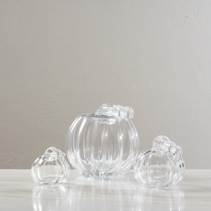 Three clear glass pumpkin-shaped containers with twisted stems, one large in center and two smaller flanking it.
