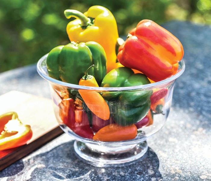 Clear glass pedestal bowl filled with red, yellow, and green bell peppers.