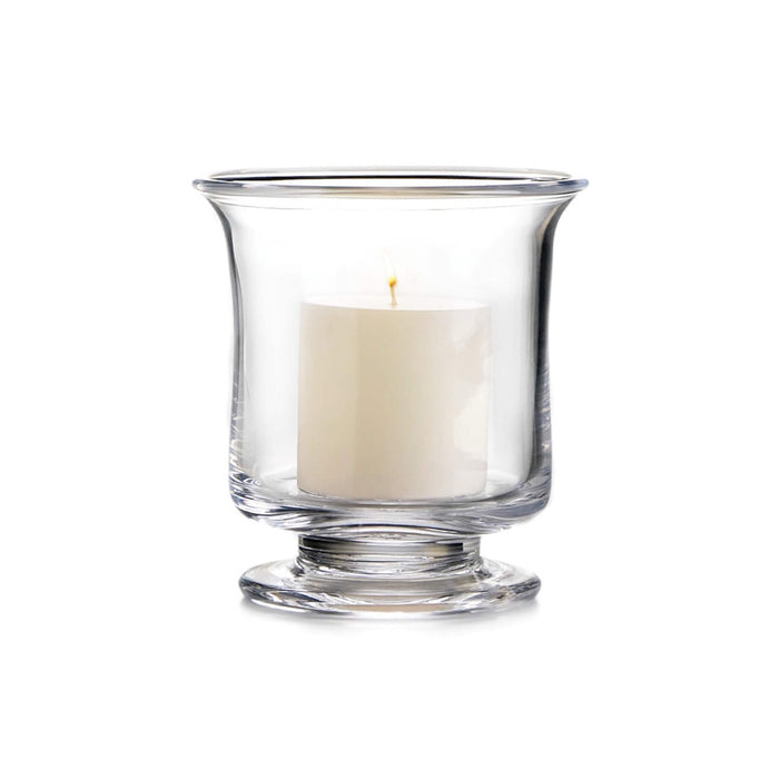 Clear glass hurricane vase with cream-colored pillar candle and yellow flame inside.