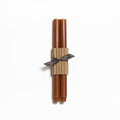 Two tall brown taper candles bundled with a tan cardboard sleeve and dark ribbon bow.