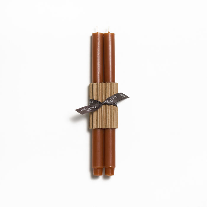 Two tall brown taper candles bundled with a tan cardboard sleeve and dark ribbon bow.
