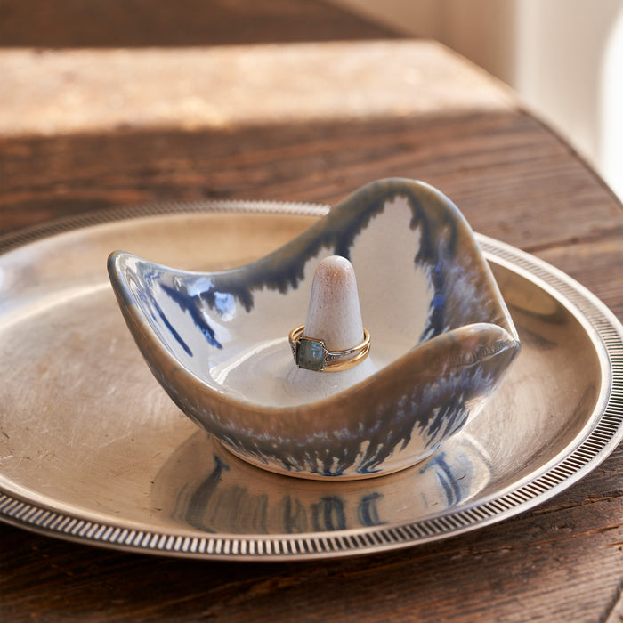 Blue and white ceramic ring holder with a small cone post, displayed on a matching plate.