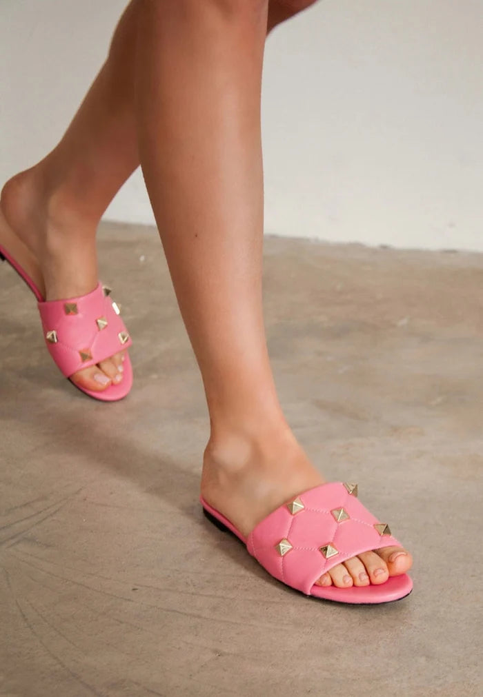 A chic pair of designer Rockstud sandals in a vibrant pink color, also known as Mila sandals, featuring the iconic studs on the straps.
