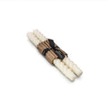 Two cream-colored tapered candles with rope-wrapped bases bound together with a black label band.