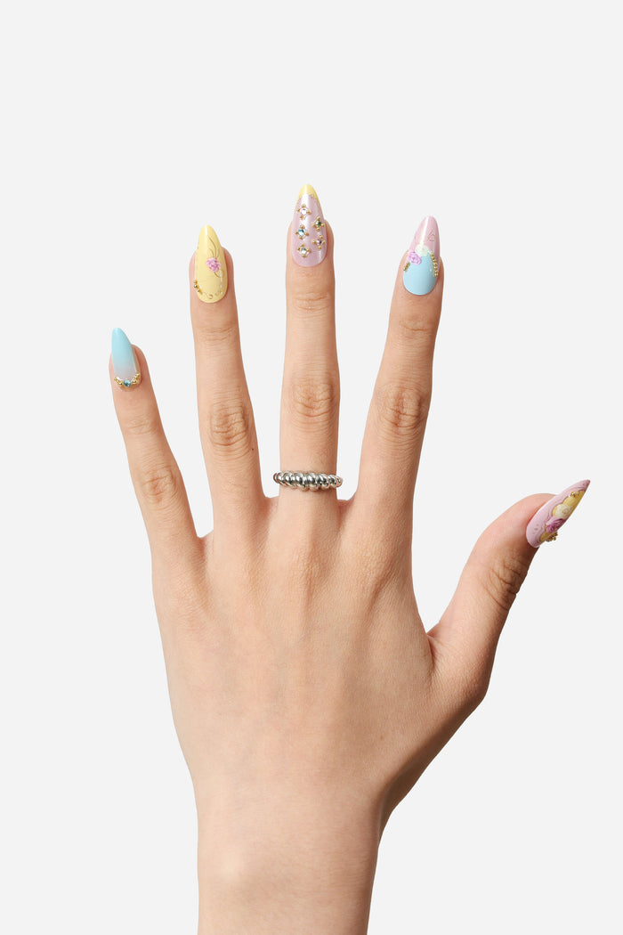 Almond press-on nails with pastel floral designs and rhinestones. Features pastel yellow, purple, and blue shades.
