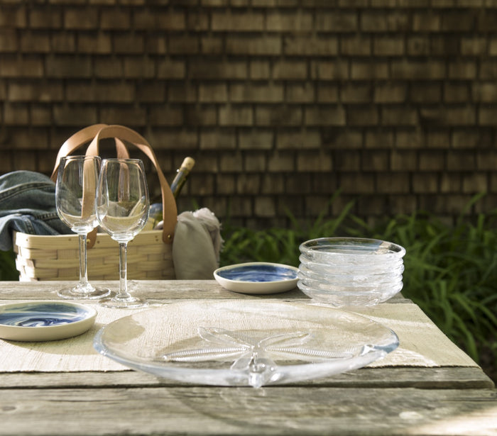 Clear glass plate with sand dollar-shaped indentations arranged in a circular pattern on the surface.