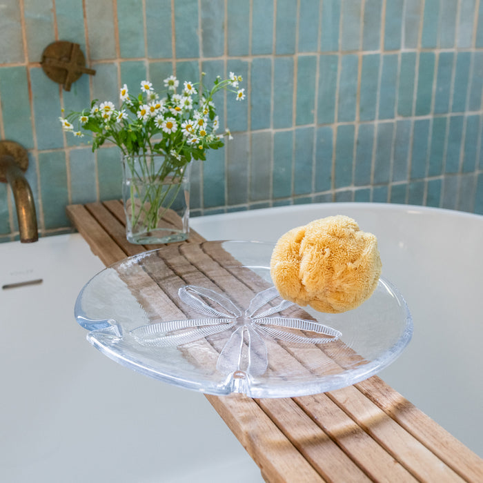 Clear glass platter with sand dollar-shaped detail and dried sea urchin shell, displayed on wooden surface.