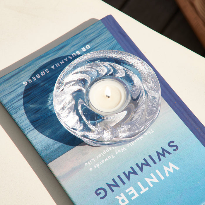 Shell-shaped silver tealight candle in clear container on blue gradient gift box.