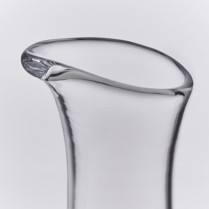 Clear glass carafe with curved sides and a pouring spout at the rim.