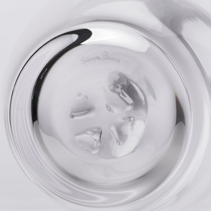 Clear glass decanter with black curved handle and etched designer signature on the body.