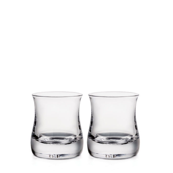 Two clear double old-fashioned glasses with curved sides and weighted bases, each holding a small amount of liquid.