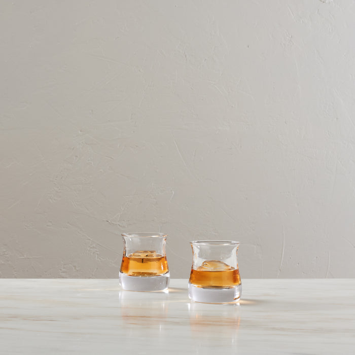 Two clear double old-fashioned glasses with white bands filled with amber liquid and ice cubes.