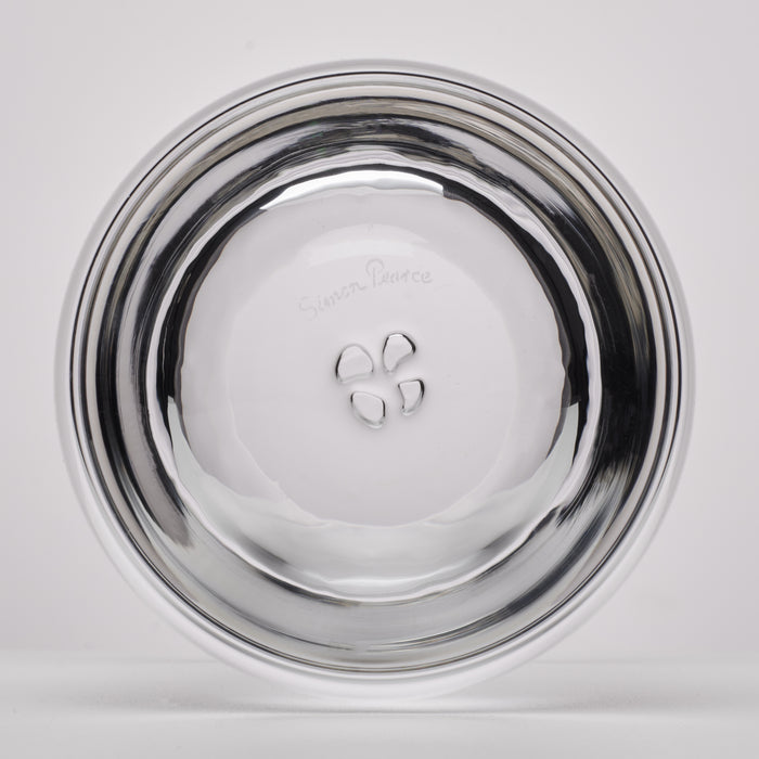 A clear glass, photographed from the bottom on a light gray background. The outside of the glass features a small embossed logo and text that appears to read 'Simon Pearce'.