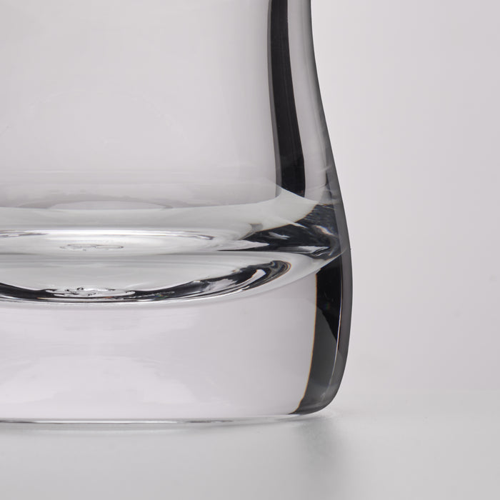 Close-up of a clear glass decanter showing the base and curved rim against a light gray background.