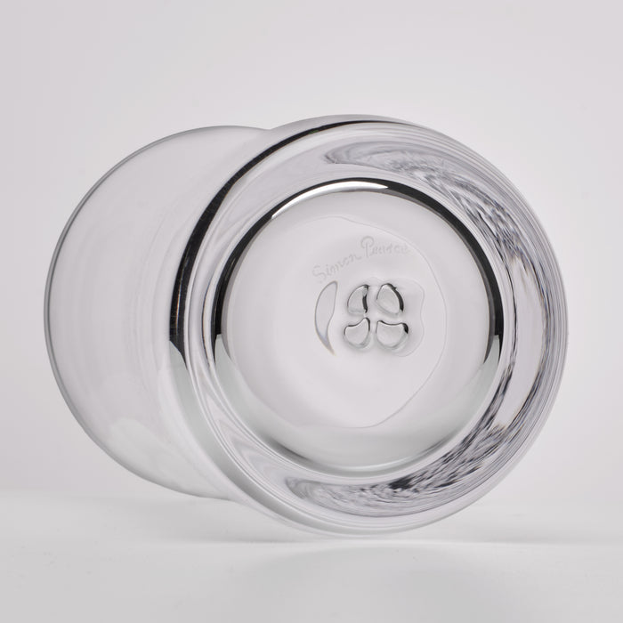 A clear glass tumbler shown from a bottom angle, featuring a thick outer rim and a thickened circular base with a logo and the words 'Simon Pearce' visible in the center.