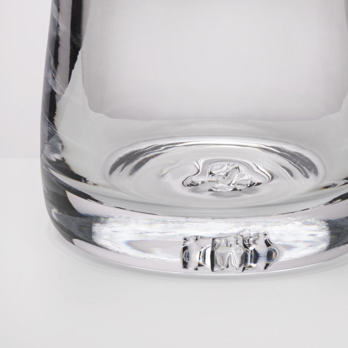 Close-up of the base of a clear glass, showing the transparent glass material and reflective surface on a white background.
