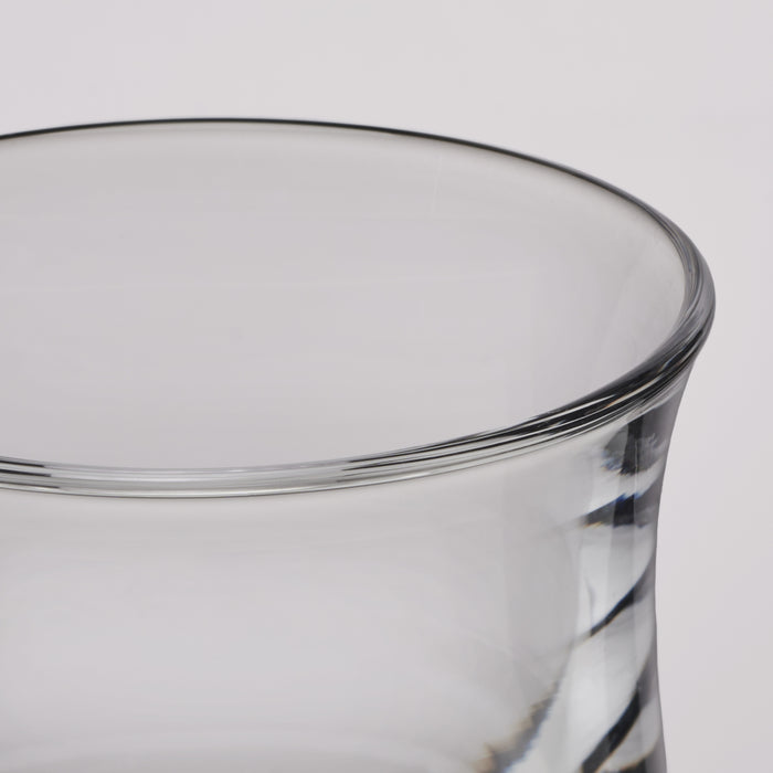 Close-up of a clear glass tumbler showing the rim and part of the twisted glass body against a light gray background.