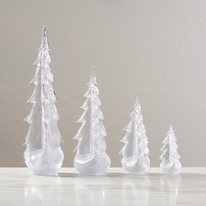 Four silver-glitter evergreen tree decorations in graduated sizes with rounded bases.