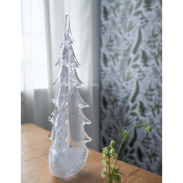 Silver-textured evergreen tree sculpture with pointed branches, displayed on wooden surface.
