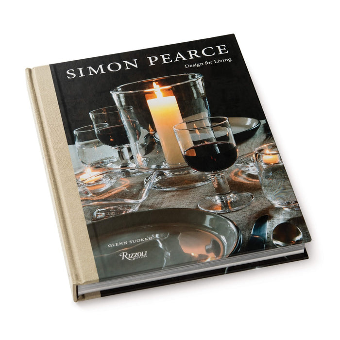 Hardcover book with black dust jacket featuring glassware, a lit candle, and place settings on the cover.