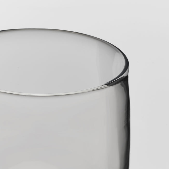 Close-up of a transparent glass showing the rim and body against a light gray background.