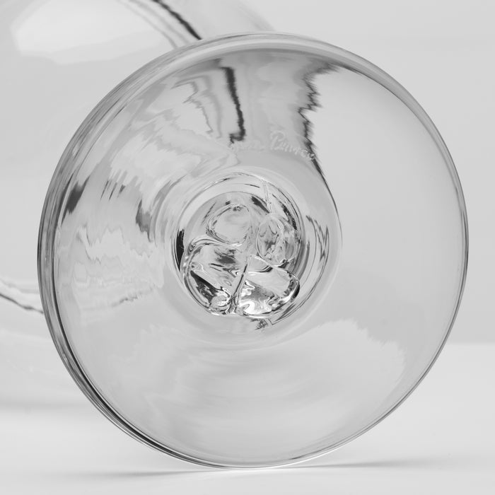 A close-up of a clear glass wine glass showing the circular base photographed on a light gray background.