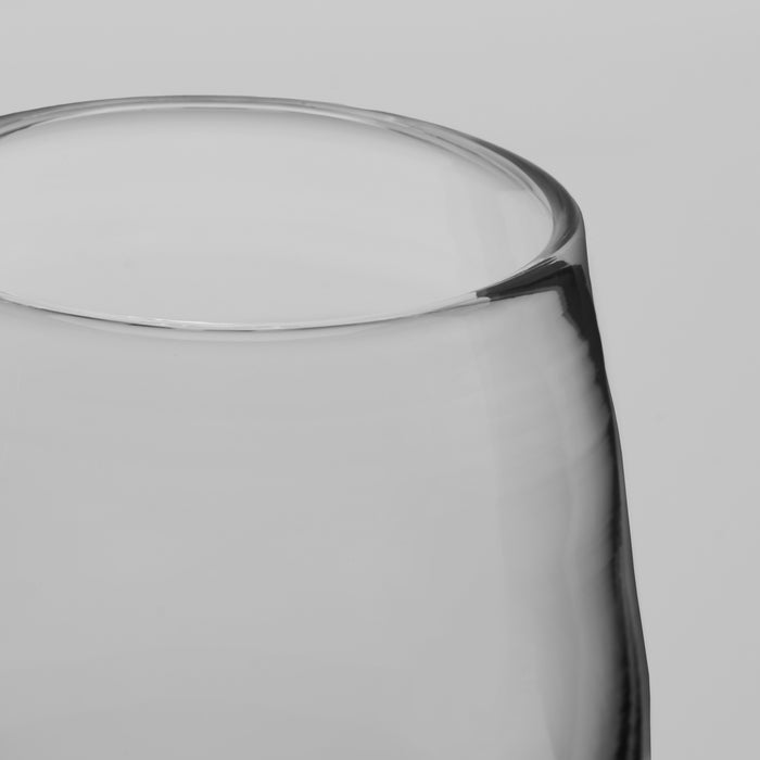 Close-up of a clear glass tumbler showing the rim and side profile against a light gray background.
