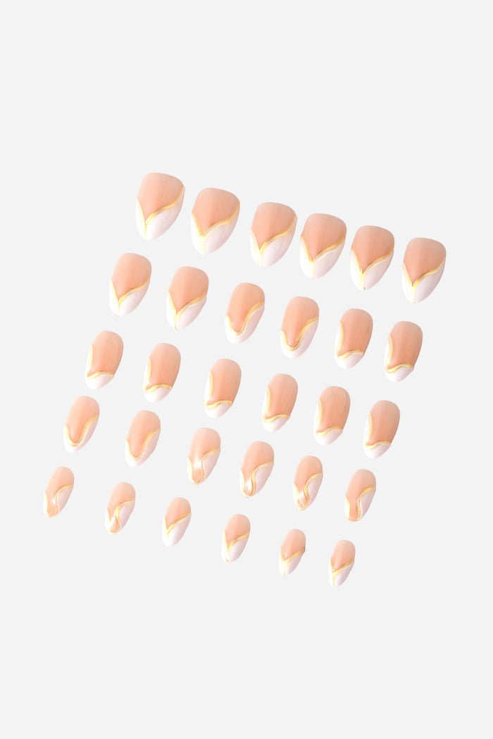 Short almond press-on nails with a nude base, white tips, and a delicate gold line accent.
