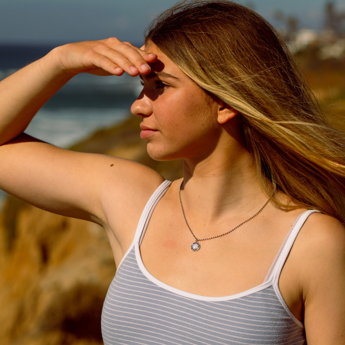 model wearing small silver black st. christopher at beach