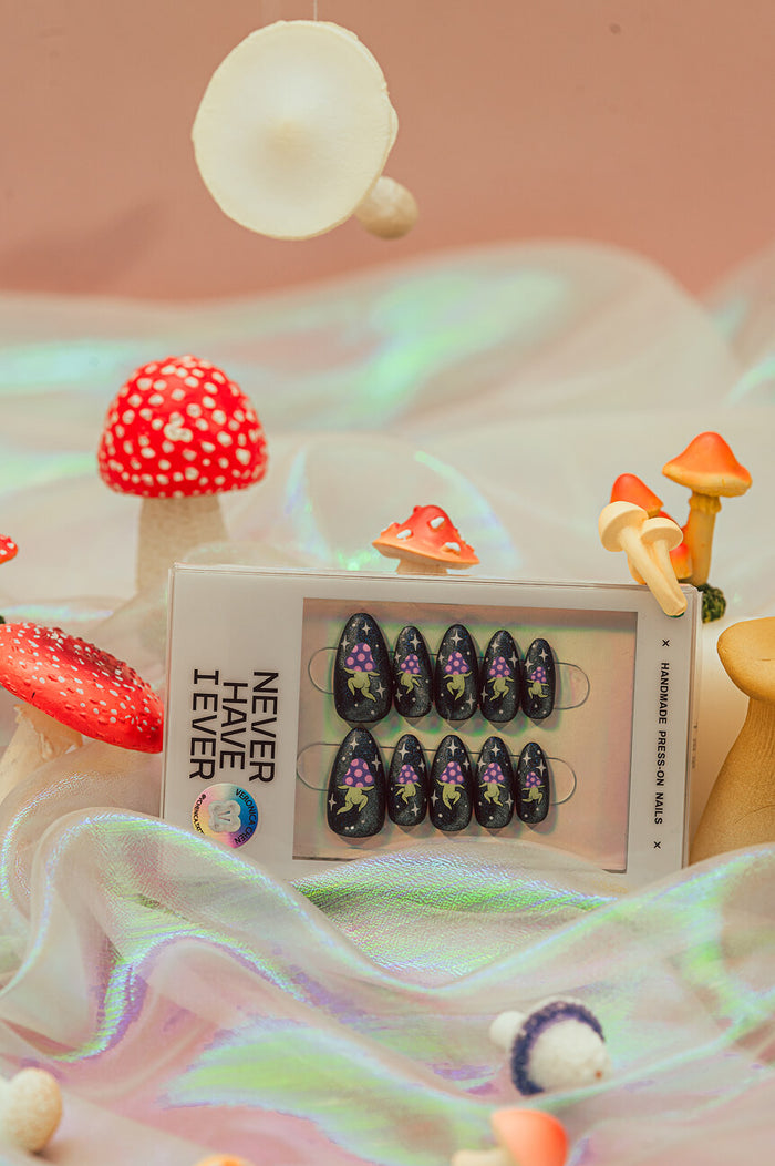 Space Rave press-on nails by Veronica Chen, featuring a dark sparkly base with purple mushroom alien figures and white stars.