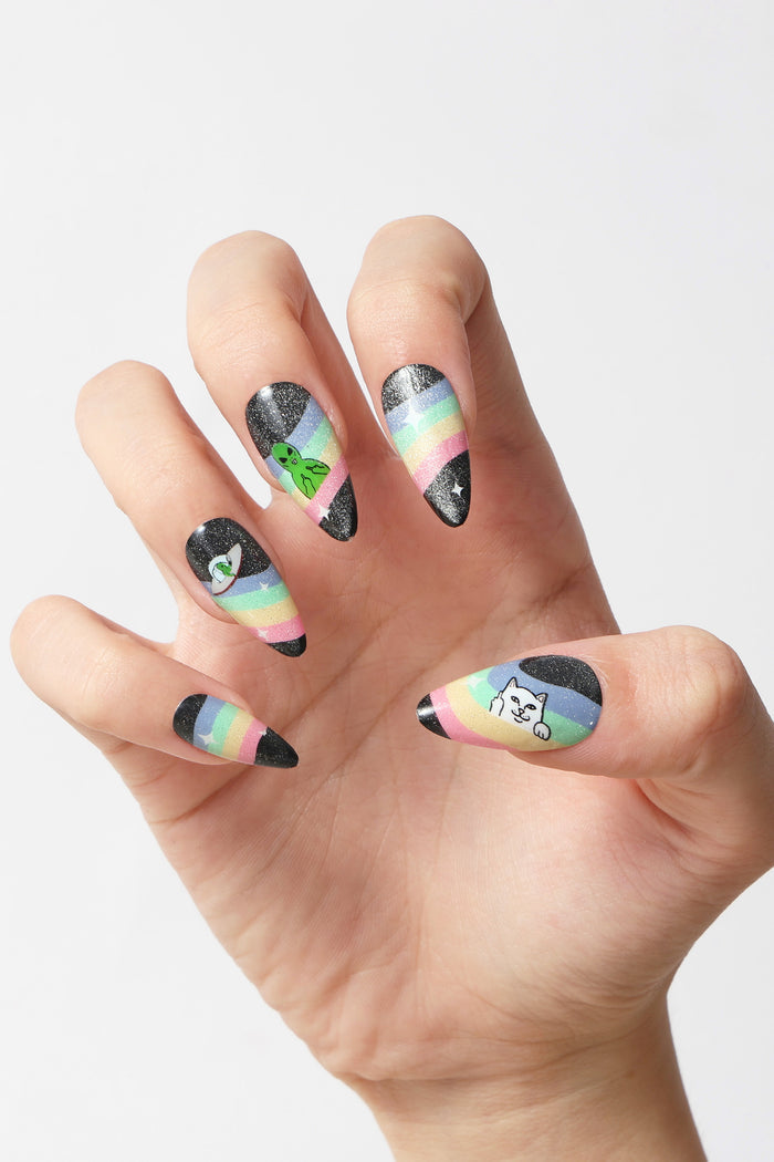 Stiletto press-on nails with black glitter, rainbow stripes, and alien and Ripndip cat designs.