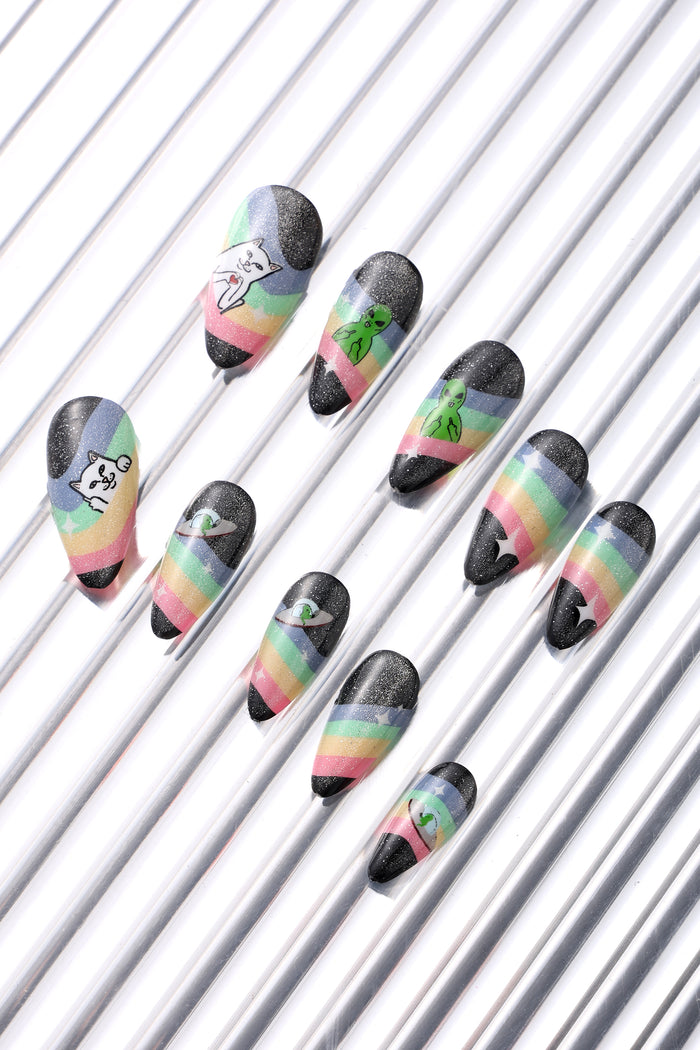 Ripndip press-on nails with rainbow stripes and playful designs like a cat holding a heart and an alien in a UFO.