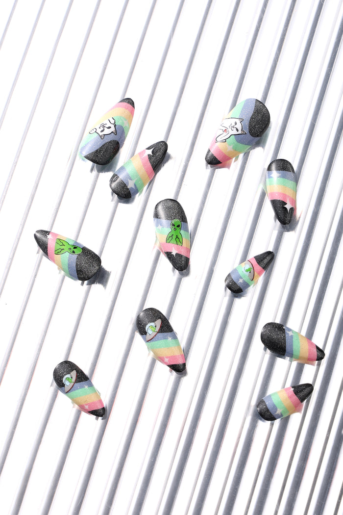 RIPNDIP SPACED OUT press-on nails with rainbow stripes and alien or cat graphics, black glitter accent.