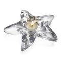 Clear glass starfish-shaped tealight holder with cream-colored candle in center and five pointed arms.